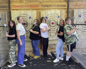 group photo of friends throwing axes